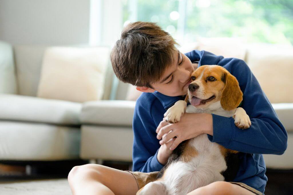 12 year old boy cuddling a dog indoors 
