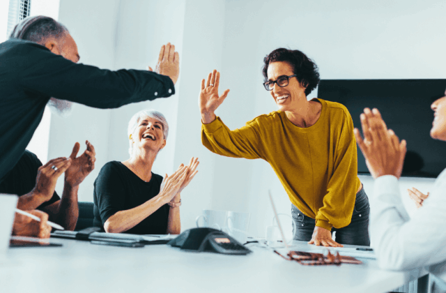 Team high-fiving and celebrating in office