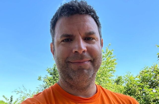 Andy Zajac outside on a sunny day with trees in the background