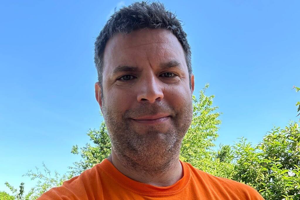 Andy Zajac outside on a sunny day with trees in the background